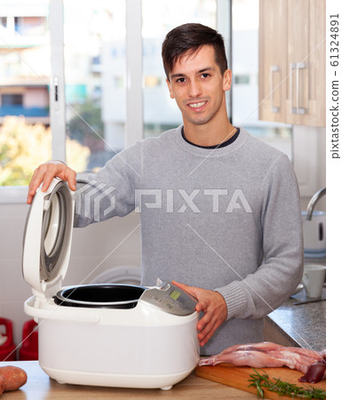 Man cooks lamb dish in electric multicooker 61324891