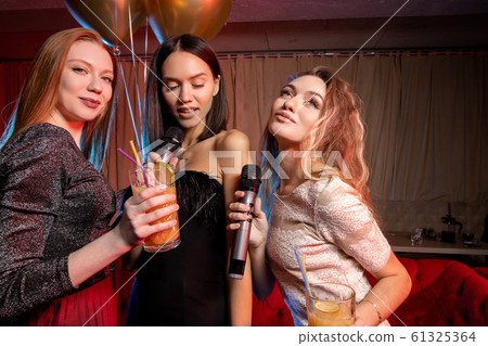 Portrait of happy caucasian women singing in microphone in karaoke bar Portrait of happy caucasian women singing in microphone in karaoke bar 61325364
