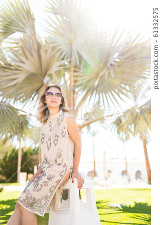 sunny photo of a charming Caucasian girl on vacation in a summer dress with a cut-out on her leg and sunny photo of a charming Caucasian girl on vacation in a summer dress with a cut-out on her leg and 61332575