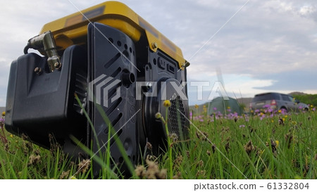 Close up of gas diesel mobile portable electricity generator work on grass. Gasoline fuel powered portable generator give electric current. 61332804