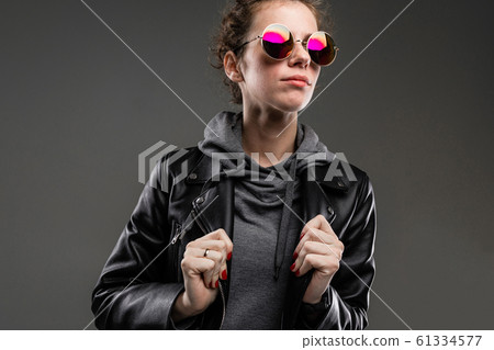 portrait of attractive caucasian girl in stylish glasses, gray sweatshirt and black leather jacket 61334577