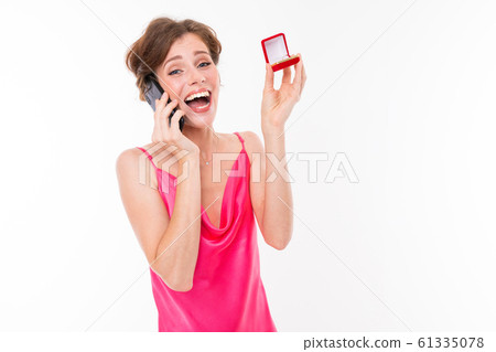 portrait of a cute happy surprised caucasian girl with a box with a ring in her hands calls on a 61335078