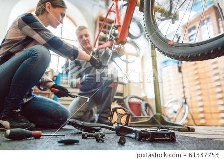 Bike mechanic working on a bicycle getting her tools 61337753