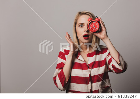 girl holds alarm clock on gray background girl holds alarm clock on gray background 61338247