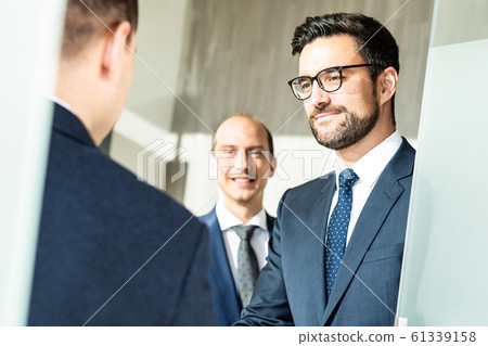 Group of confident business people greeting with a handshake at business meeting in modern office or closing the deal agreement by shaking hands. 61339158