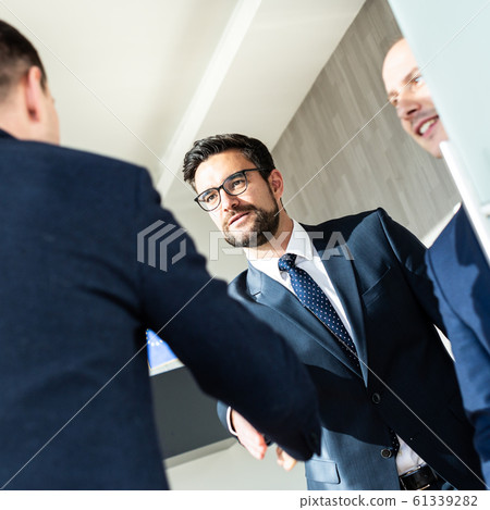 Group of confident business people greeting with a handshake at business meeting in modern office or closing the deal agreement by shaking hands. Group of confident business people greeting with a handshake at business meeting in modern office or closing the deal agreement by shaking hands. 61339282
