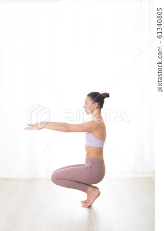 Portrait of gorgeous active sporty young woman practicing yoga in studio. Beautiful girl practice Utkatasana, awkward yoga pose. Healthy active lifestyle, working out in gym 61340805