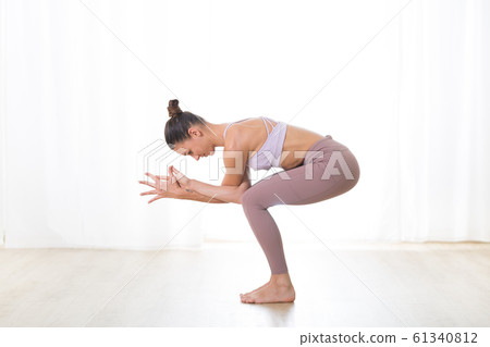 Portrait of gorgeous active sporty young woman practicing yoga in studio. Beautiful girl practice Garurasana, eagle yoga pose. Healthy active lifestyle, working out indoors in gym 61340812