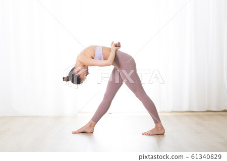 Portrait of gorgeous active sporty young woman practicing yoga in studio. Beautiful girl practice Dandayamana Bibhaktapada Jauushirasana, standing separate leg head to knee pose 61340829