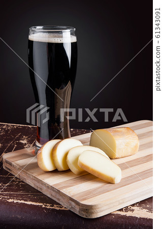 Glass with dark beer with smoked cheese on cutting Glass with dark beer with smoked cheese on cutting 61343091