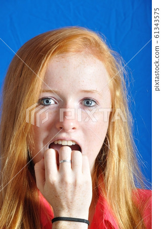 Scared teen on blue background Scared teen on blue background 61343575