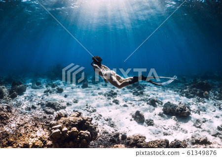 Woman free diver with fins glides underwater in deep ocean 61349876