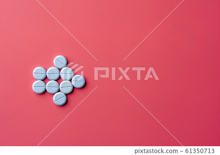 Close-up of bkue pills lie on a pink surface Close-up of bkue pills lie on a pink surface 61350713