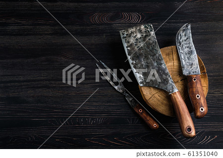 Old butcher meat knife, cleaver and fork on black 61351040