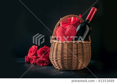 Valentines day gift hamper, bouquet of red roses, bottle of sparkling wine on black. Valentines day gift hamper, bouquet of red roses, bottle of sparkling wine on black. 61351689