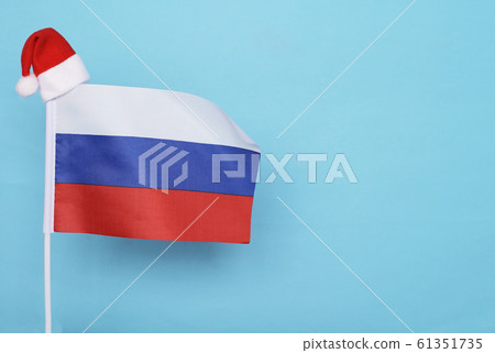 Flag of Russia with little santa claus hat on blue background. New Year winter holiday concept, copy space Flag of Russia with little santa claus hat on blue background. New Year winter holiday concept, copy space 61351735