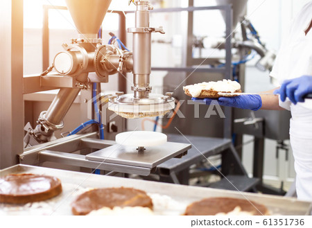 Modern equipment for the manufacture of cakes. Smear cream on cake. Confectionery, automatic Modern equipment for the manufacture of cakes. Smear cream on cake. Confectionery, automatic 61351736