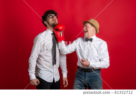 Studio shot of young versus old generation, a father and son with boxing glove. 61352712