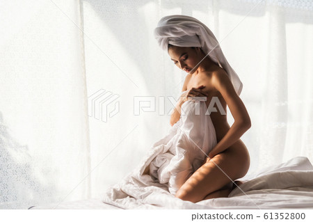 Naked woman on bed after showering 61352800