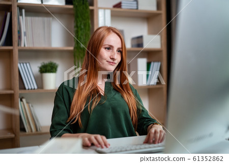 Young businesswoman sitting at the desk indoors in office, using computer. Young businesswoman sitting at the desk indoors in office, using computer. 61352862