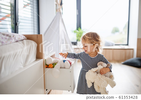 Cute small toddler girl indoors in bedroom playing. Cute small toddler girl indoors in bedroom playing. 61353428