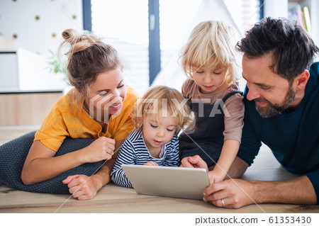 Young family with two small children indoors in bedroom, using tablet. Young family with two small children indoors in bedroom, using tablet. 61353430