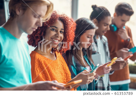 Student smiling standing near friends and using social media Student smiling standing near friends and using social media 61353789