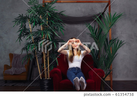 Full length of a beautiful sexy woman sitting in red armchair in dark studio 61354738