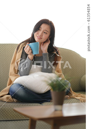 A woman drinking coffee on the sofa A woman drinking coffee on the sofa 61354854
