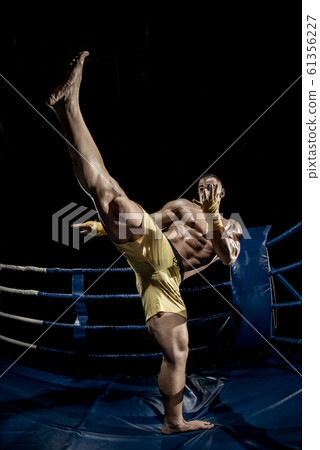 Thai boxer on boxing ring, kicking 61356227