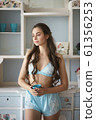 Beautiful woman standing near window with coffee in turquoise pajama set - camisole and shorts 61356253