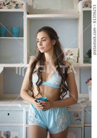 Beautiful woman standing near window with coffee in turquoise pajama set - camisole and shorts 61356253