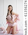 Beautiful young woman smiling sensually on the bed playing with her pink pajama set 61356274