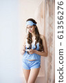Beautiful woman standing near window with coffee in blue pajama set - camisole and shorts with lace 61356276
