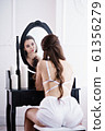 young woman sitting at dressing table in white pajama set 61356279