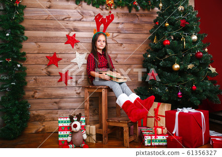 Funny child girl writes letter to Santa near christmas tree Funny child girl writes letter to Santa near christmas tree 61356327