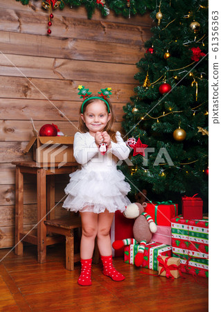 beautiful happy small girl with christmas ball near Christmas tree at home 61356363