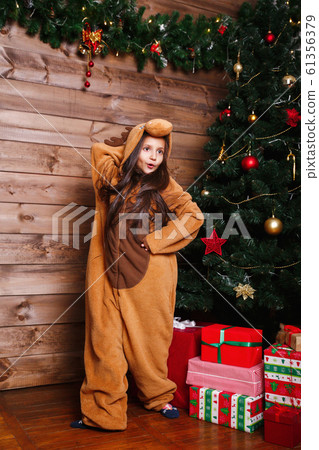 Funny little girl in pajamas jumping and having fun near Christmas tree Funny little girl in pajamas jumping and having fun near Christmas tree 61356379