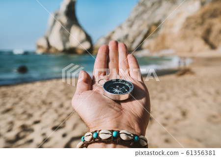 Man hand with compass symbolling adventure-seeking concept against Ursa beach, Sintra, Portugal 61356381