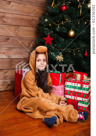 Funny little girl in pajamas sitting with gift box near Christmas tree Funny little girl in pajamas sitting with gift box near Christmas tree 61356382