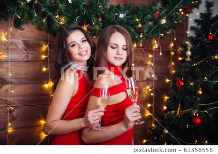 Two happy women in red dresses drinking champagne and celebrating Christmas 61356558