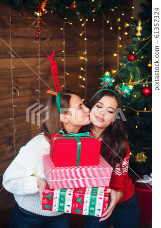 Friends presenting gifts each other near Christmas tree Friends presenting gifts each other near Christmas tree 61357324