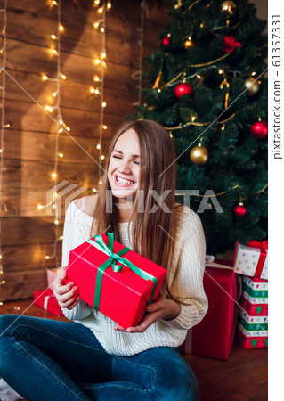 Beautiful woman posing in room surrounded by Christmas presents. Beautiful woman posing in room surrounded by Christmas presents. 61357331