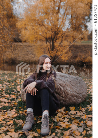 Young stylish girl sitting outdoor in autumn scenery Young stylish girl sitting outdoor in autumn scenery 61357473