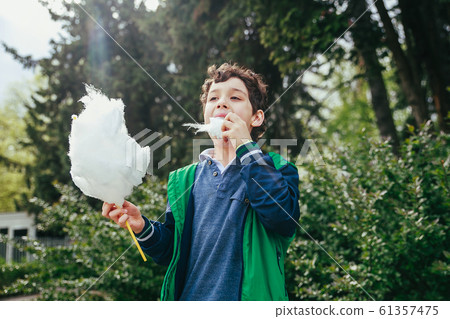 Happy child eating cotton candy at carnival in park 61357475