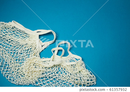 Replacing plastic bags.Taking care of the environment. Empty mesh, awosika on a blue background. Replacing plastic bags.Taking care of the environment. Empty mesh, awosika on a blue background. 61357932