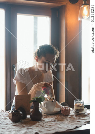Lonely girl sitting in a cafe and eating dessert. Lonely girl sitting in a cafe and eating dessert. 61358285