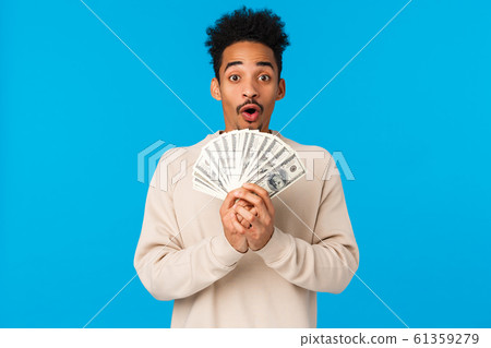 Lottery, sport bet and finance concept. Amazed and startled happy african-american guy got lots of cash, winning prize, holding big money and smiling, gasping astonished, blue background 61359279