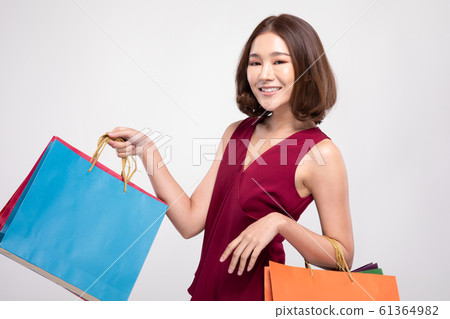 Shopping Asian woman with short hairs smile wearing red dress Holding Shopping bags,Cheerful and Happiness enjoy shopping in black friday sale,Isolated on gray background 61364982