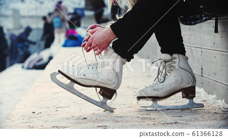 A woman hands untie her figure skates 61366128